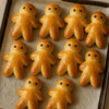 Petits manalas dorés en forme de bonhommes, alignés sur une plaque de cuisson recouverte de papier sulfurisé.