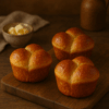 Brioche express individuelle, dorée et moelleuse, présentée sur une planche en bois dans une ambiance chaleureuse et rustique.